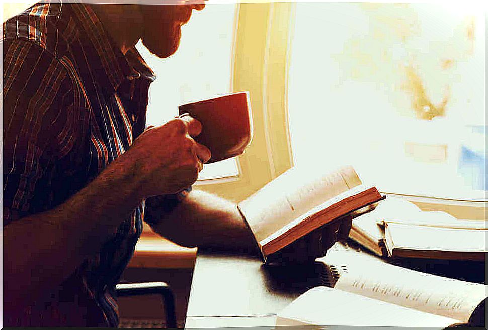 man with coffee reads a book