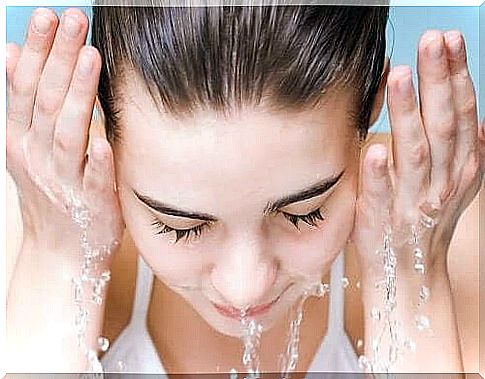 A woman washes her face with water