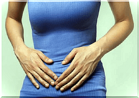 Woman with hands on stomach against stomach cramp
